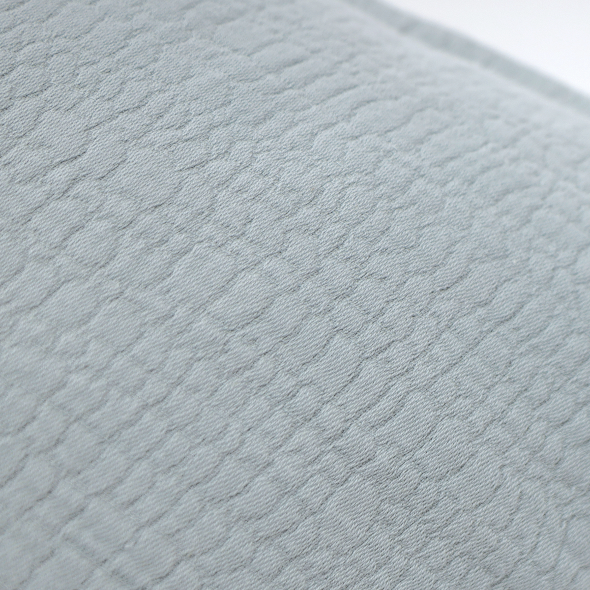 Close-up of light blue-gray textured pillow fabric with subtle woven pattern